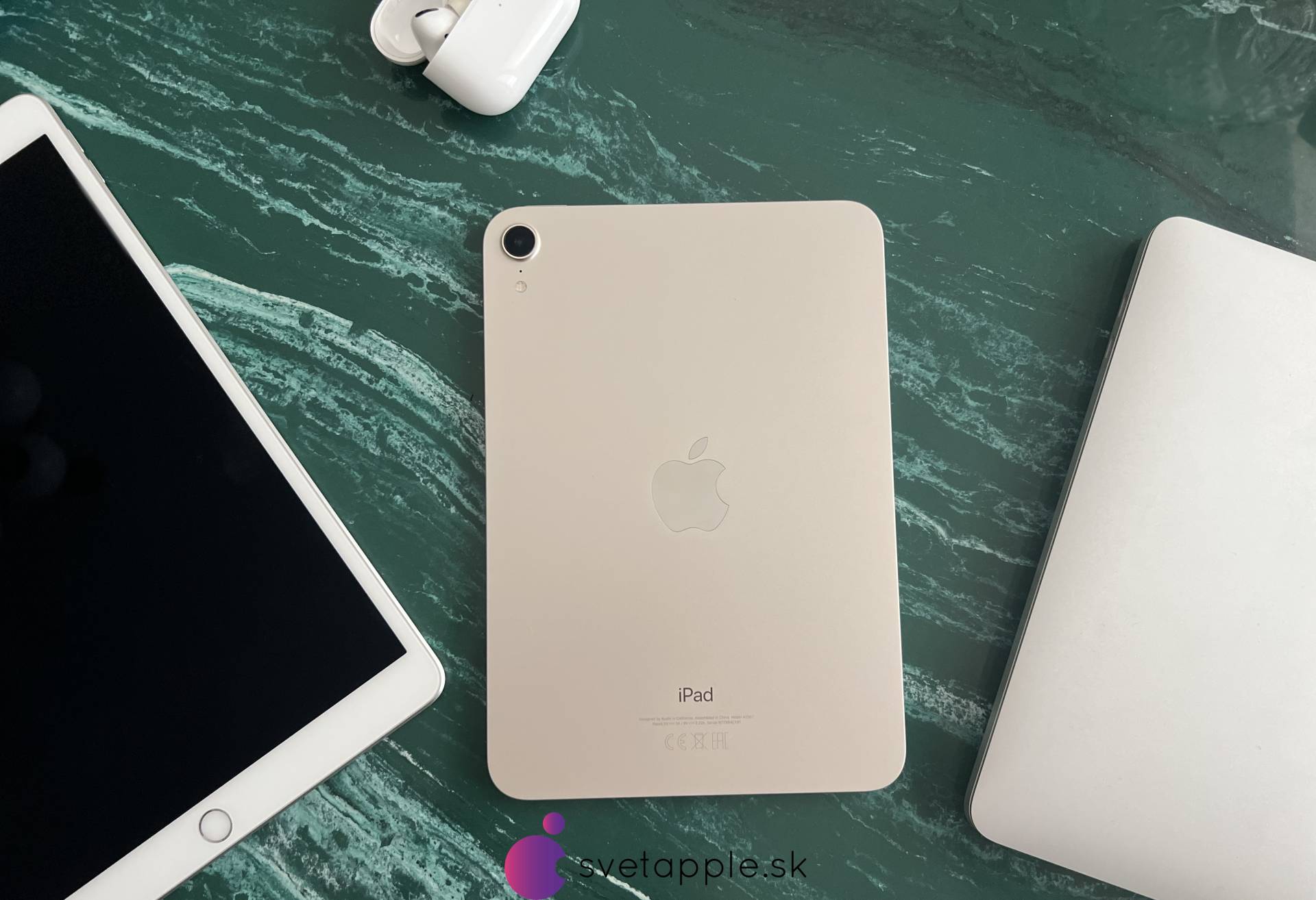 iPad mini 6 na zelenom stole vedľa AirPods Pro, iPadu Air 3. generácie a MacBooku Pro