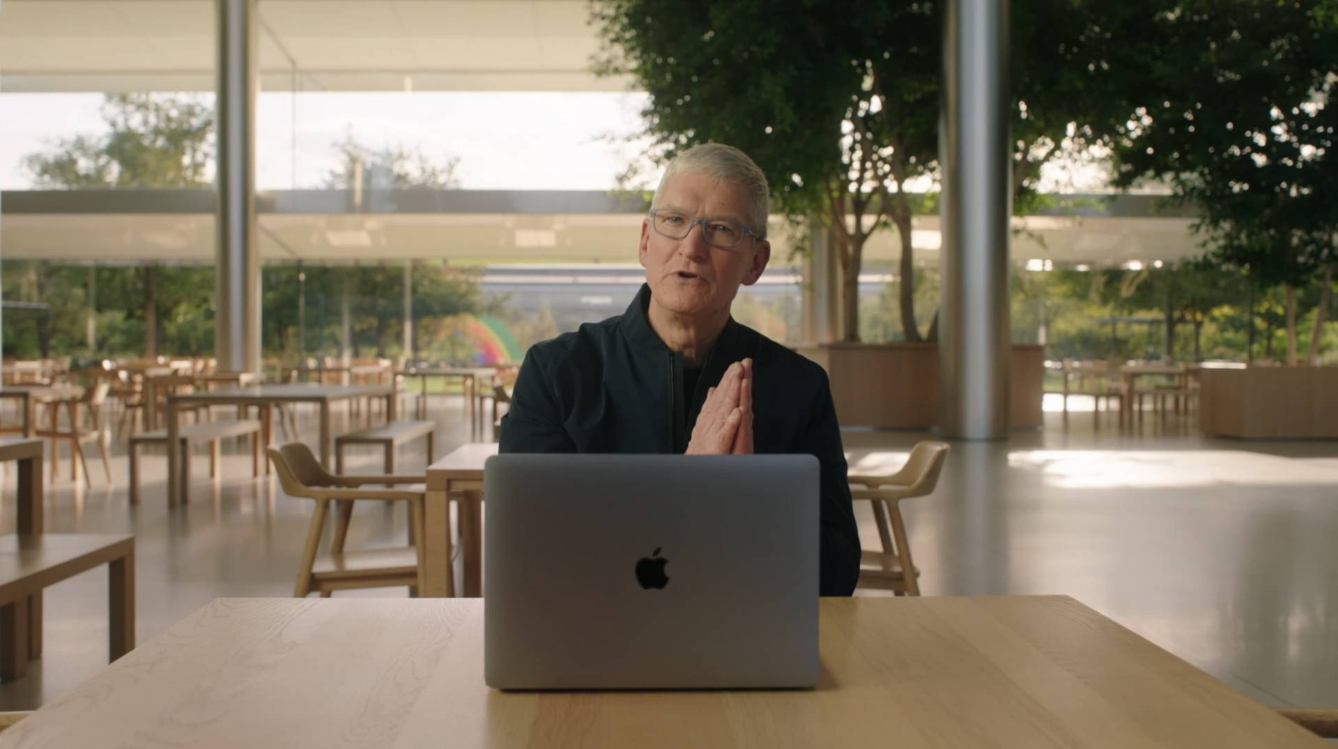 Tim Cook sedí za stolom s počítačom MacBook