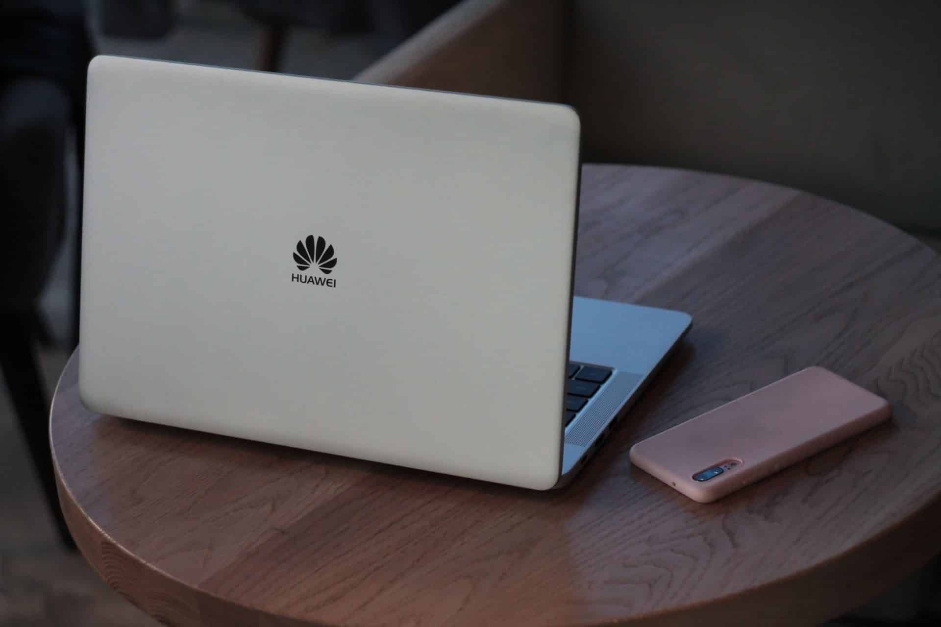 Notebook a smartfón od spoločnosti Huawei položený na drevenom stole
