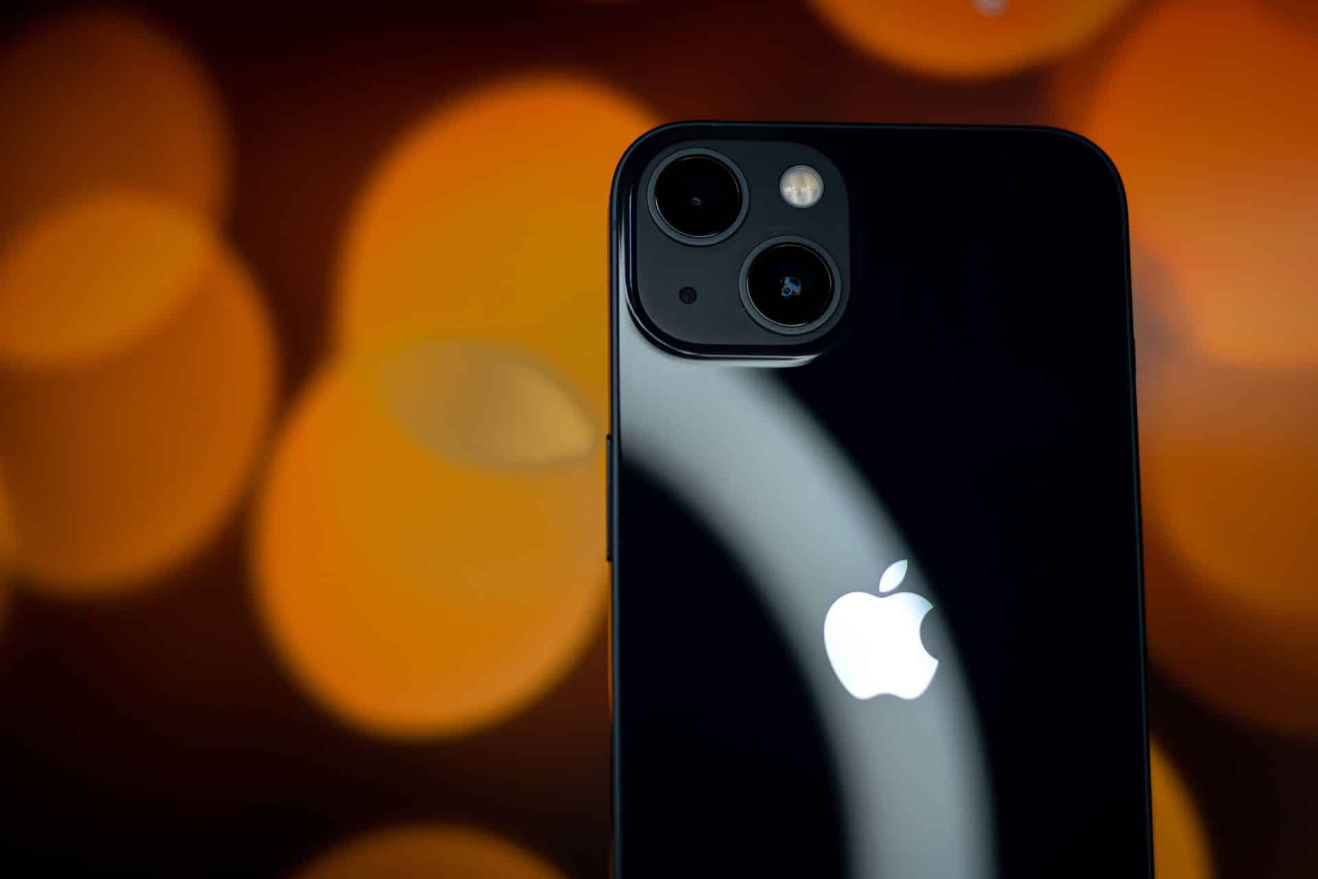 iPhone 13 v čiernej farbe s oranžovým pozadím