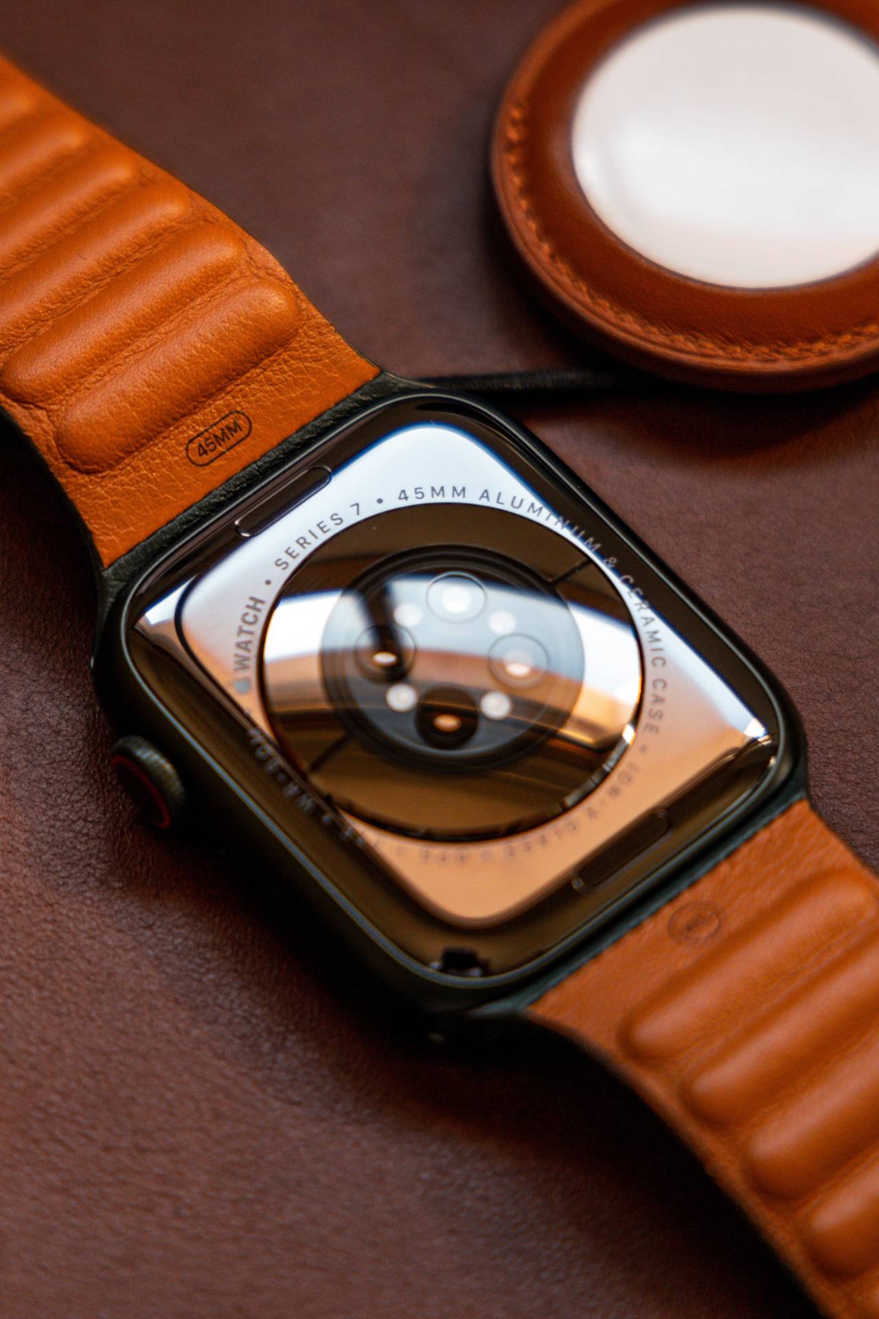 Apple Watch Series 7 zo zadnej strany, kde sú senzory. Hodinky majú hnedý kožený remienok