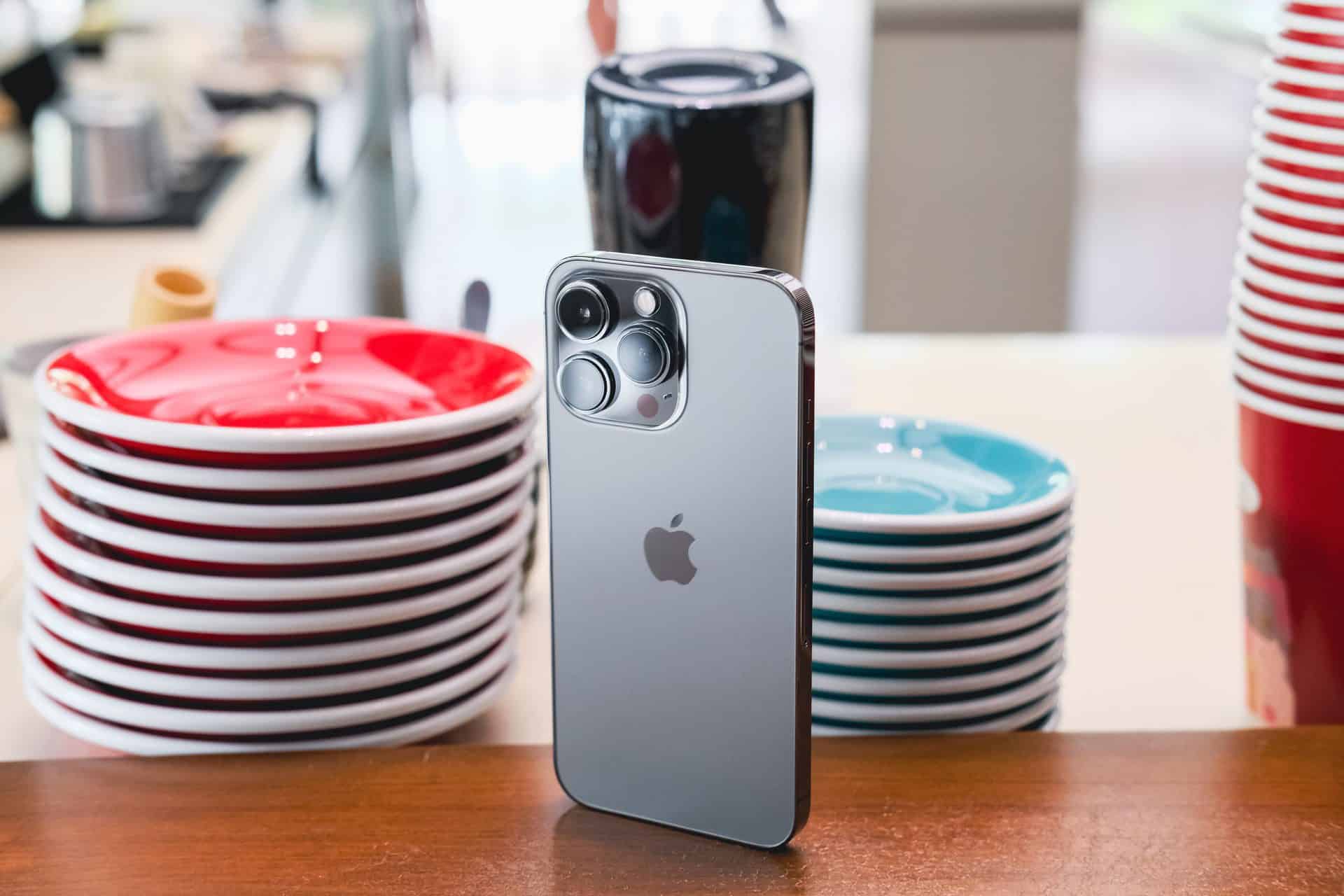 iPhone 13 Pro vo svetlo sivej farbe graphite zo zadnej strany s taniermi v pozadí