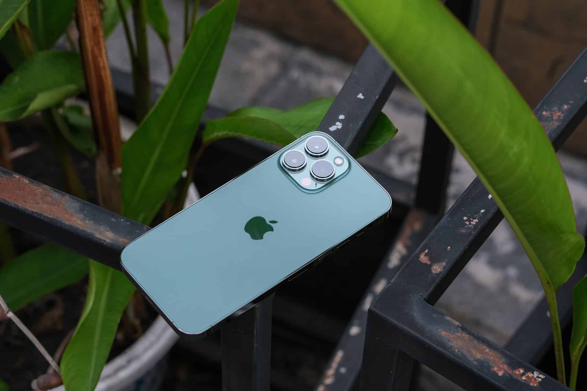 Apple iPhone 13 Pro Max Alpine Green (zelený) 2022 položený na kovovom zábradlí