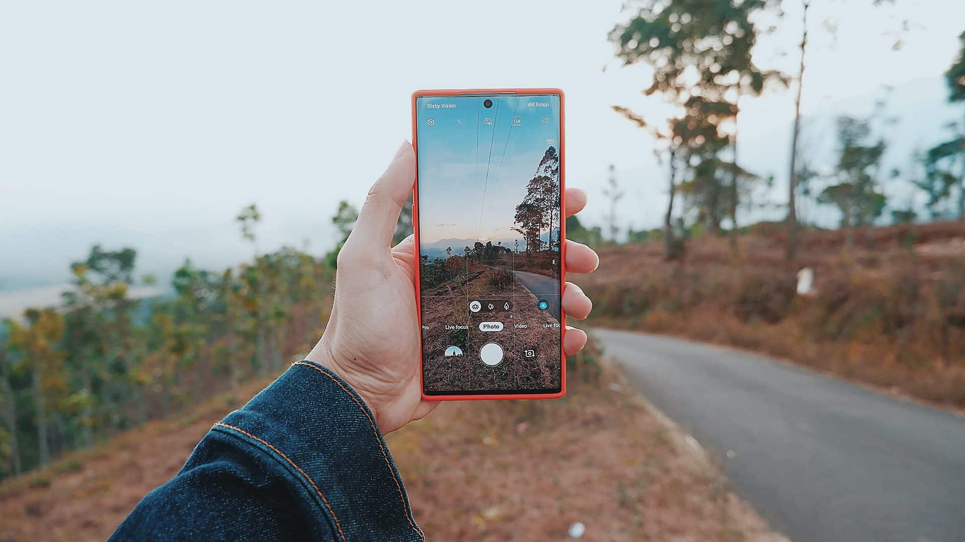 Samsung Galaxy Note 10 v červenej farbe so zapnutým fotoaparátom v nádhernom lesnom prostredí
