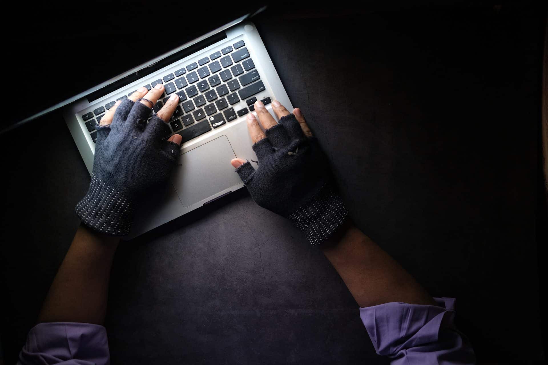 hacker v rukaviciach pred počítačom